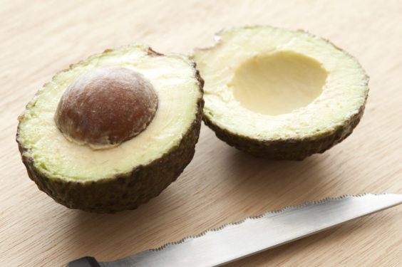 Close-up of cut fresh avocado and knife on wooden table