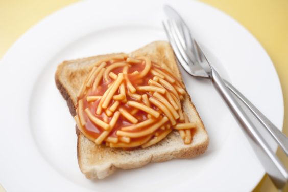 Cheap quick snack of canned spaghetti in tomato sauce on a slice of white toast served on a plate