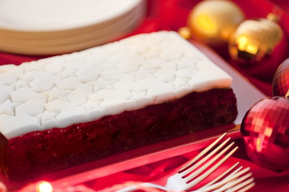 Traditional Christmas fruit cake with decorative white icing with stars served on a Christmas table with colourful baubles
